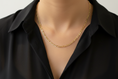 Load image into Gallery viewer, Close-up of a person wearing a 14K gold-filled Figaro chain necklace over a white shirt.
