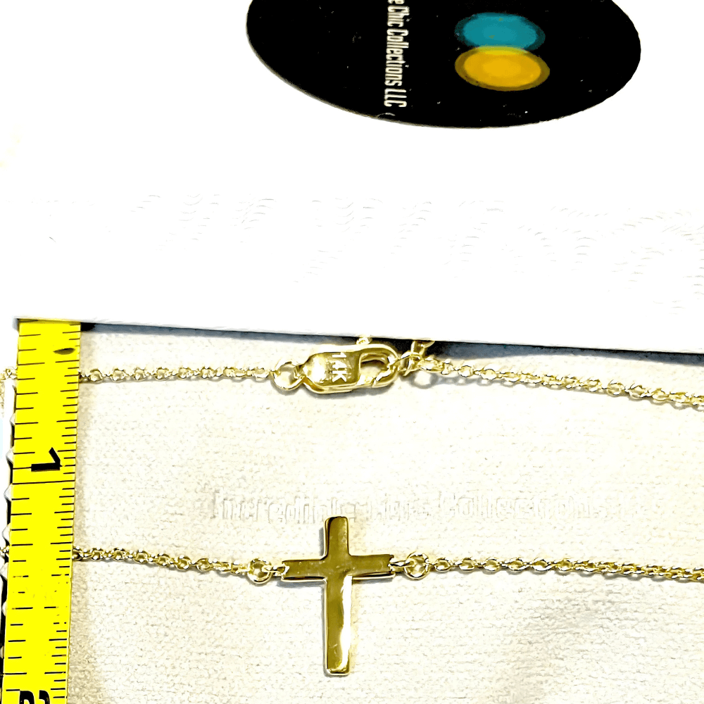 14k gold cross necklace displayed on a box, featuring a tiny cross pendant and measuring tape for size reference.