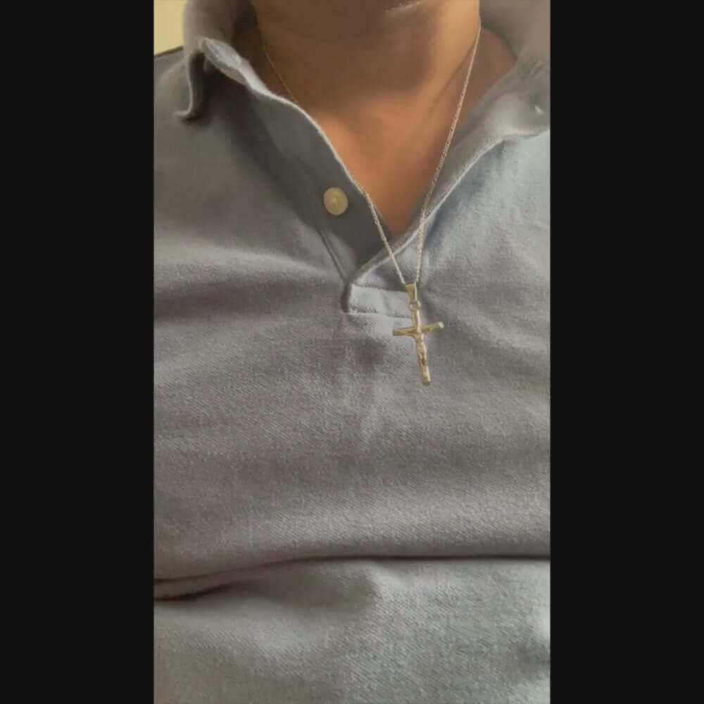 Close-up of a person wearing a 14k white gold cross necklace, showcasing its elegance and design on a polo shirt.