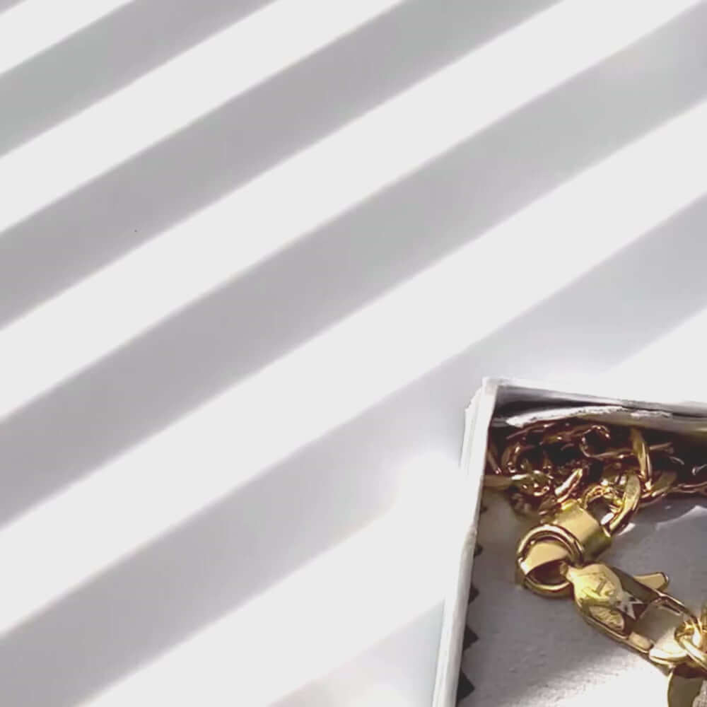 14k gold-filled Figaro chain necklace displayed in a box with soft sunlight creating striped shadows.